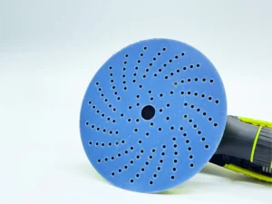 Blue zirconia alumina sanding disc with multiple holes mounted on sander in workshop setting