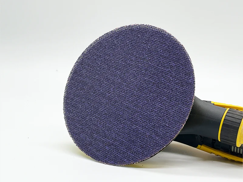 Purple ceramic net mesh sanding disc, zirconia alumina abrasive, attached to power tool in workshop setting
