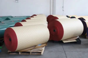 Large orange ceramic abrasive paper jumbo roll in a workshop setting, used for making high-performance sanding discs