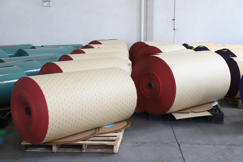 Large orange ceramic abrasive paper jumbo roll in a workshop setting, used for making high-performance sanding discs
