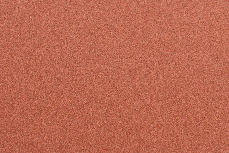 Close-up of red ceramic sanding disc surface, showing abrasive grain and durable backing for professional use